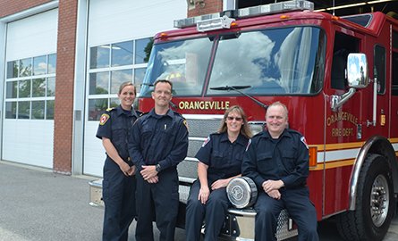 group of fire staff in front of building and truck